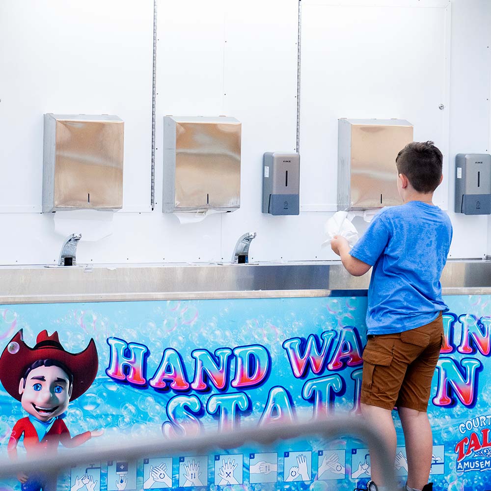 A young guest washes their hands at Talley Amusements' handwashing station