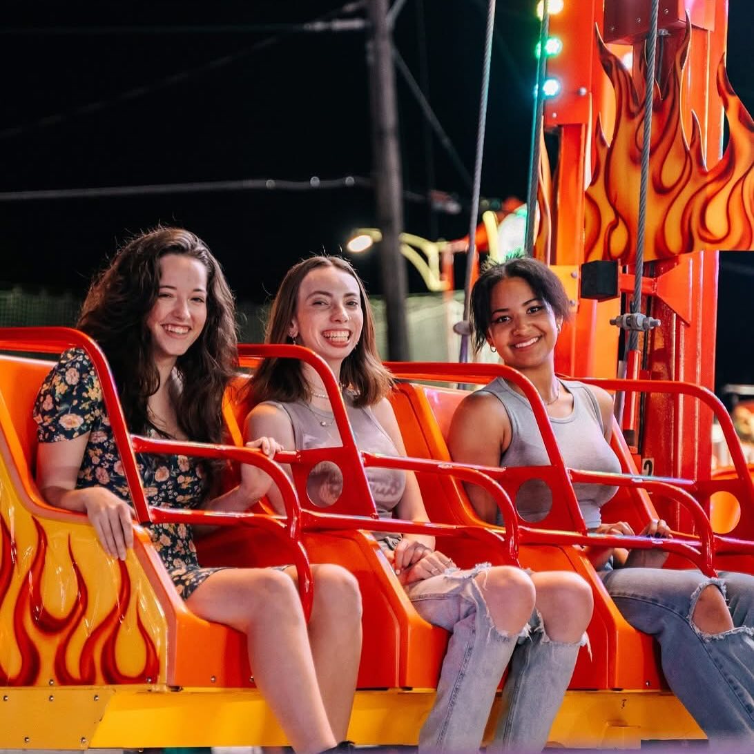 Three young women ride an exciting thrill ride at Talley Amusements carnival